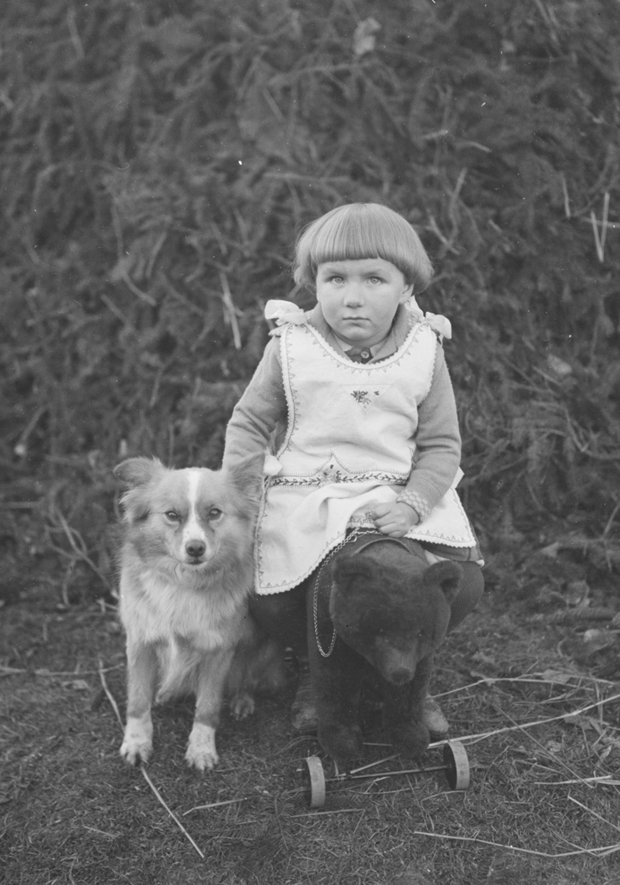 Historisches Foto von Kind, das neben einem Hund sitzt