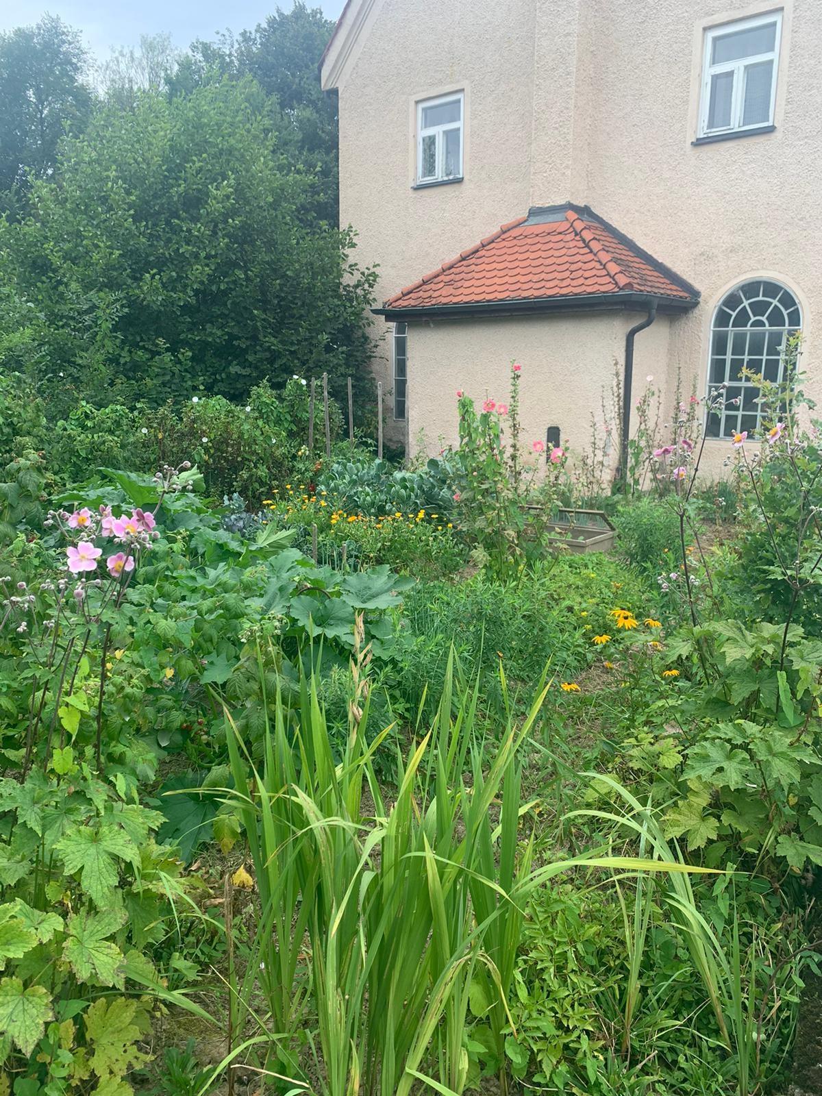 blühender Garten mit Schmiede im Hintergrund