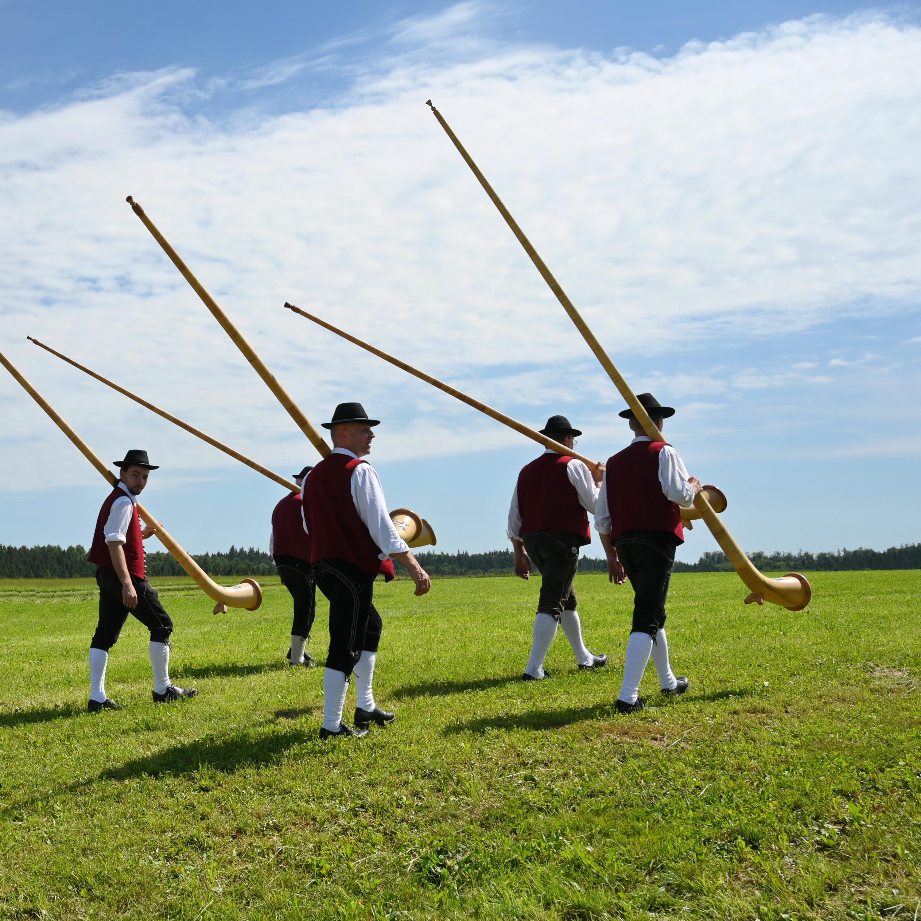 mehrere Musiker in Tracht tragen Alphörer auf der Schulter