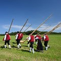 Musiker in Tracht laufen und tragen Alphörner