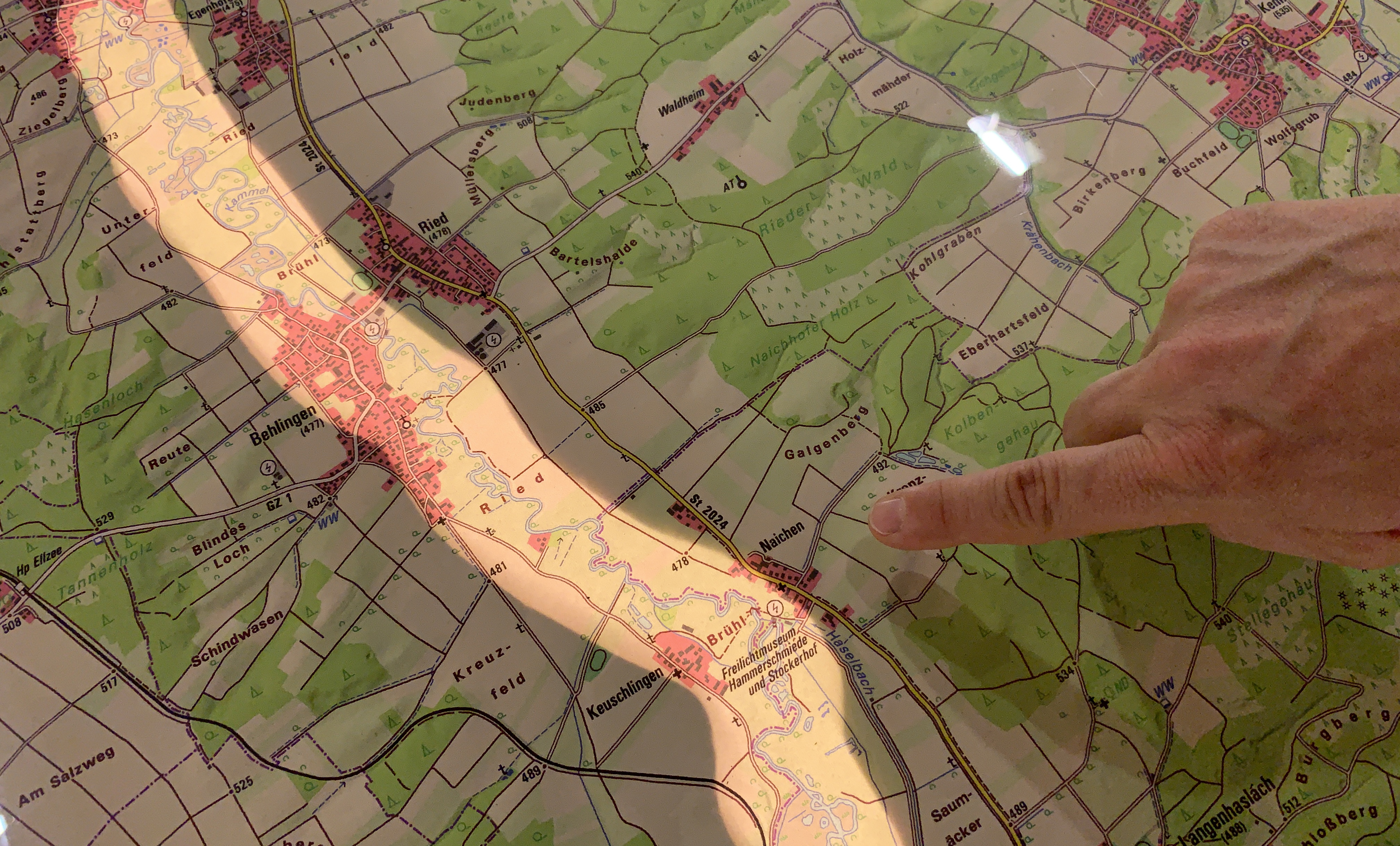Finger zeigt auf Landkarte mit beleuchtetem Streifen entlang Flusslauf
